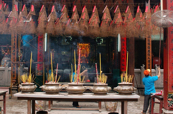 HO CHI MINH CITY - Suggestive spirali di incenso pendono dal soffitto della Pagoda di Thien Hau mentre lucidi vasi di ottone bruciano bastoncini di incenso