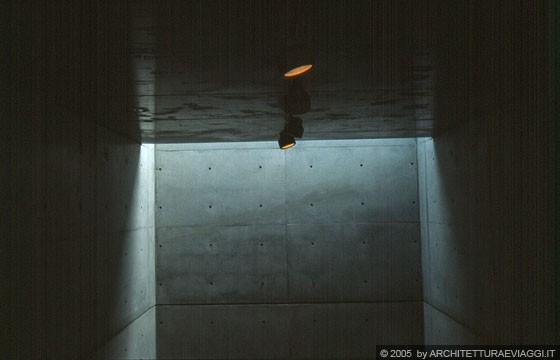 TOKYO SENGAWA - Tokyo Art Museum (TAM) - la luce filtra dal soffitto enfatizzando la verticalità della stretta parete di calcestruzzo