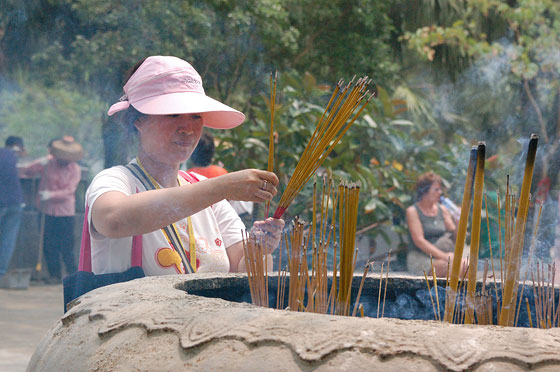 MONASTERO DI PO LIN - Rituali buddhisti: una cinese brucia bastoncini di incenso nel grande braciere nei pressi degli edifici del monastero