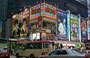 MONG KOK. Angolo con Nathan Road: ampi manifesti e insegne pubblicitarie vestono gli stipati condomini