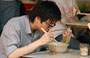 WAN CHAI. Dal nostro tavolino fotografiamo questo cinese mentre pranza all'interno del dai pai dong di fronte a noi, gustando un piatto di tagliolini in brodo con bacchette e cucchiaio