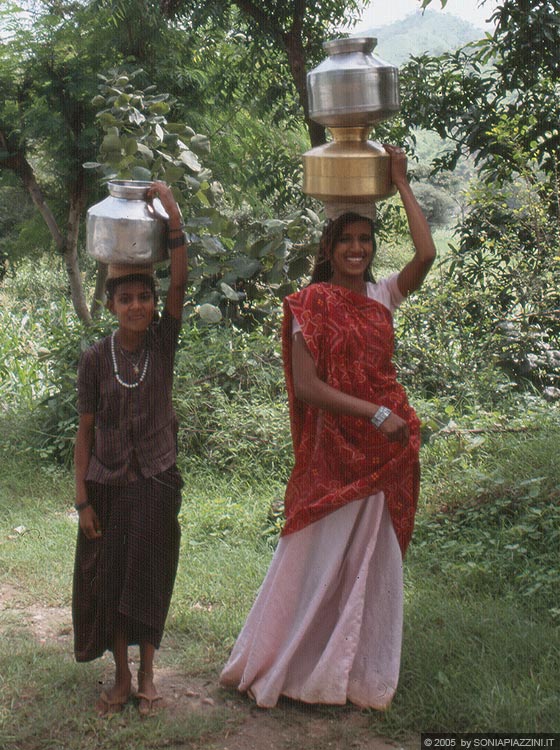 RAJASTHAN MERIDIONALE - Due giovani ragazze camminano trasportando sulla testa stoviglie nelle le campagne tra Udaipur e Kumbhalgarh 