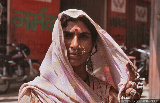 VILLAGGIO DI KUMBHALGARTH - Una donna indiana accetta fiera di posare per la macchina fotografica: indossa bracciali, molti anelli e il caratteristico anello al naso e sulla fronte ha disegnato il cerchio rosso 