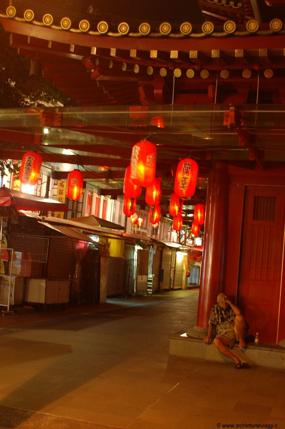 SINGAPORE - Un anziano cinese sonnecchia sui gradini del Buddha Tooth Relic Temple, illuminato dalle belle lanterne rosse