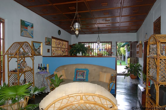 CHORONI' - Il soggiorno dell'abitazione tra piante, mobili in bambù e soffitti lignei
