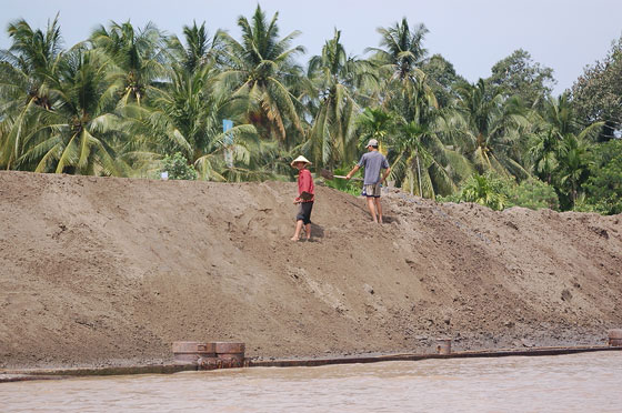 VERSO IL DELTA DEL MEKONG - Il trasporto della sabbia sul fiume attraverso chiatte, con uomini al lavoro