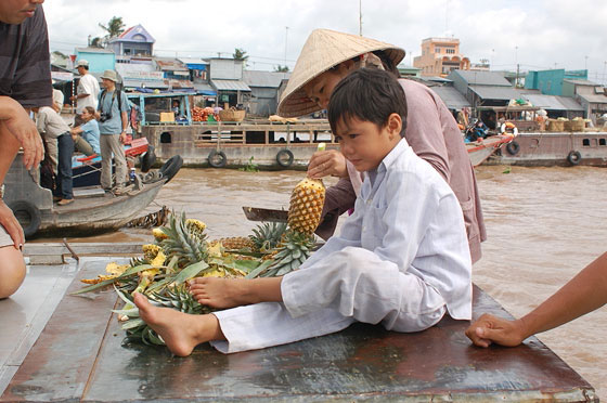 DELTA DEL MEKONG - Mercato galleggiante di Cai Rang: la venditrice ci sbuccia l'ananas quasi fosse una scultura