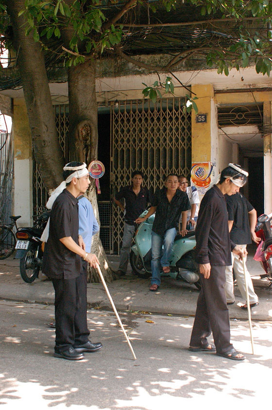 HANOI - Uomini con la fascia bianca e il bastone comandano la processione di un funerale