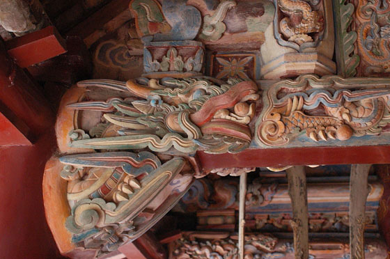 HOA LU - Duong Van Nga - portico esterno: particolare di una trave in legno riccamente decorata