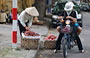 HANOI. Due donne in motorino si fermano a comprare frutta da una venditrice ambulante