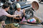 HANOI. Una venditrice ambulante pesa la frutta con una vecchia stadera